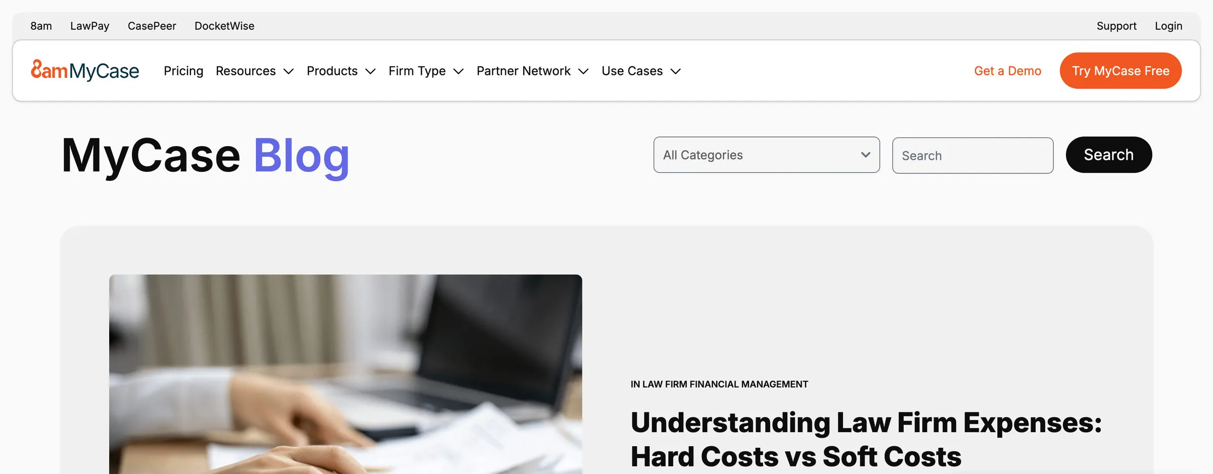 The MyCase blog index. The cross-brand rail and the 8am MyCase navigation sit above a heading reading “MyCase Blog”, beside an All Categories dropdown, a search field and a Search button. Below, a featured post is tagged “In Law Firm Financial Management” and titled “Understanding Law Firm Expenses: Hard Costs vs Soft Costs”, with a named author and headshot.